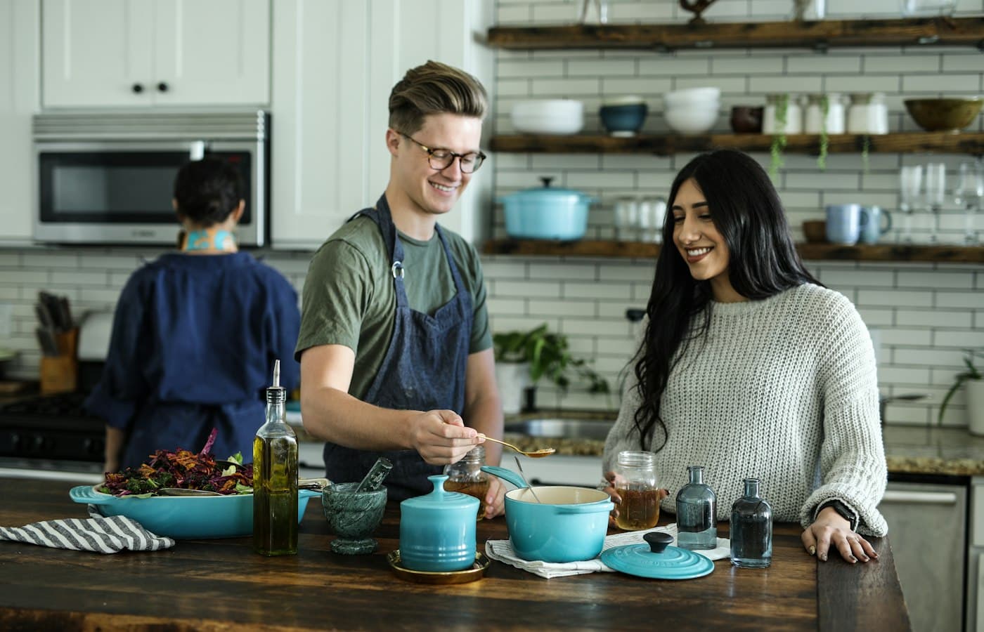 People cooking in a kitchen with bowls, bottles, and cookware